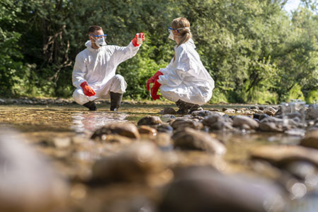 Environmental scientists take water samples in a stream