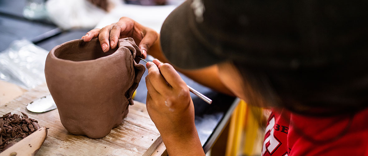 A JSU art student carves fine details into her clay sculpture.