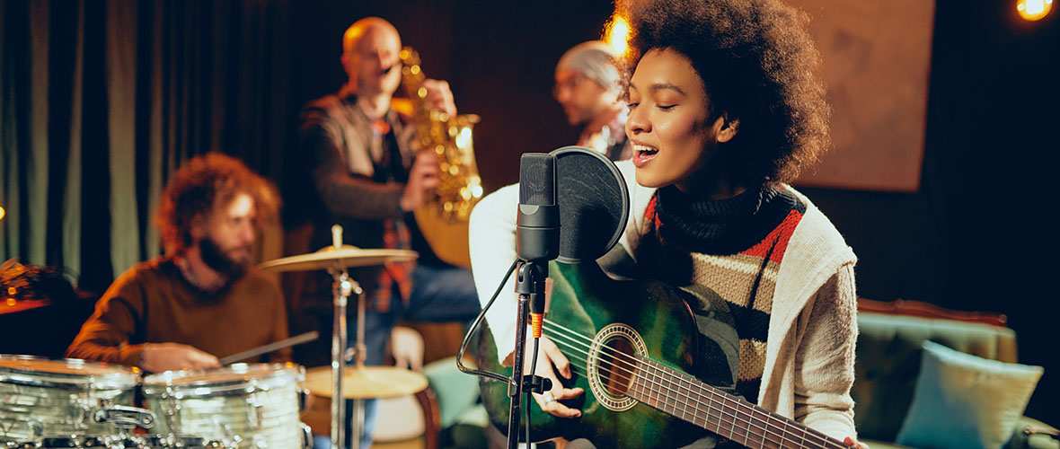 Guitarist singing with musicians in studio