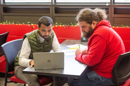 Two people working on writing. 
