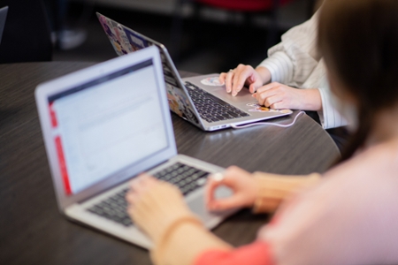 Two JSU students are displayed studying on their computers.