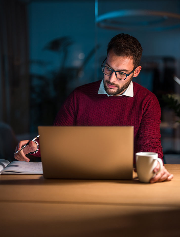 A male student sits at his computer, working on online classes