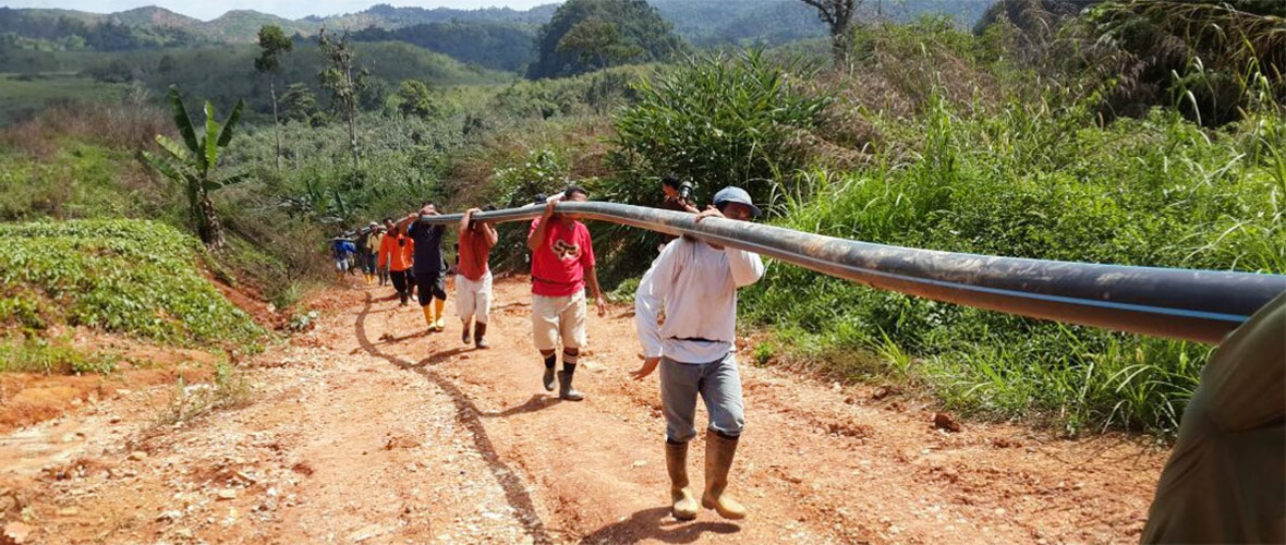 Public Health worker helps carry a water line Ito a remote area of the jungle.