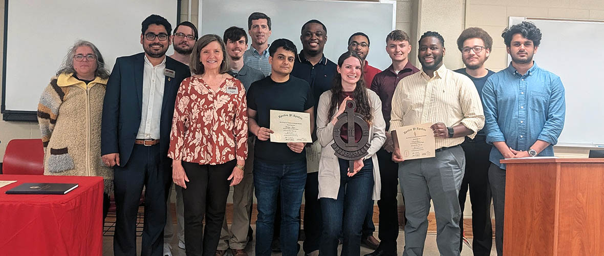 UPE inductees stand behind their banner and key