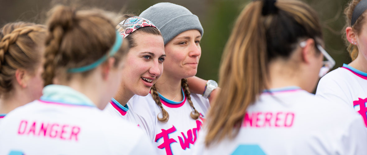 Female teammates huddle during an ultimate frisbee game.